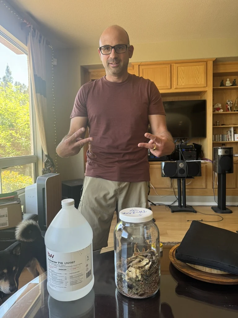 Practitioner preparing an original batch of Dit Da Jow, with medicinal herbs in a glass jar and extraction alcohol